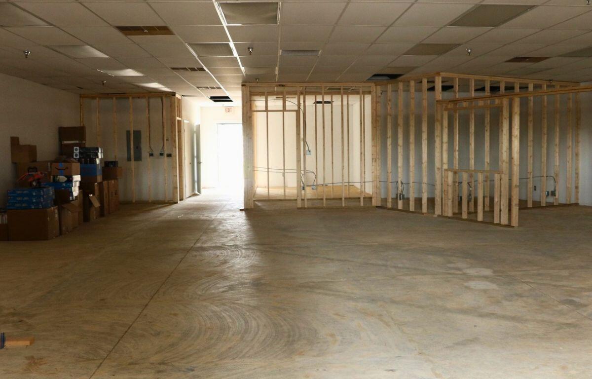 A dark, open room with wooden support beams and light shining through a door.