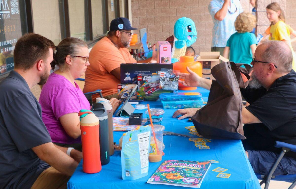 A table on an open store strip with Legos and customers.