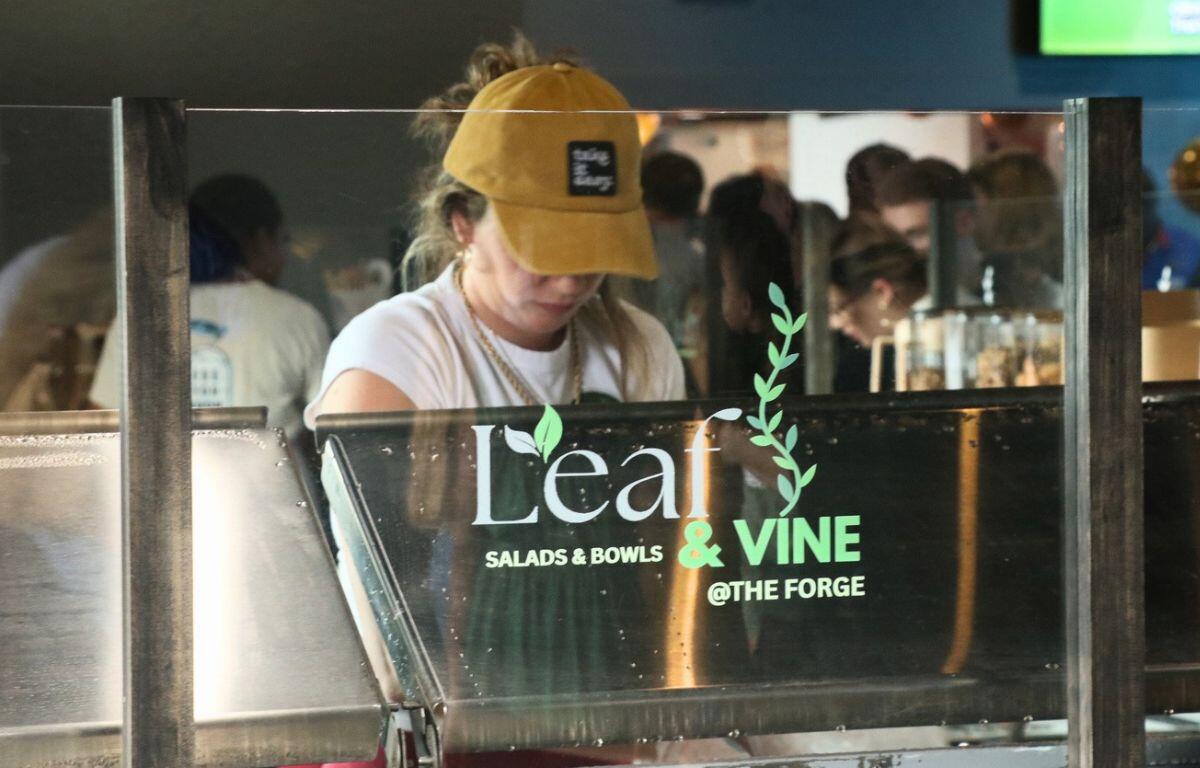 A woman behind glass. Printed on the glass, "Leaf & Vine."