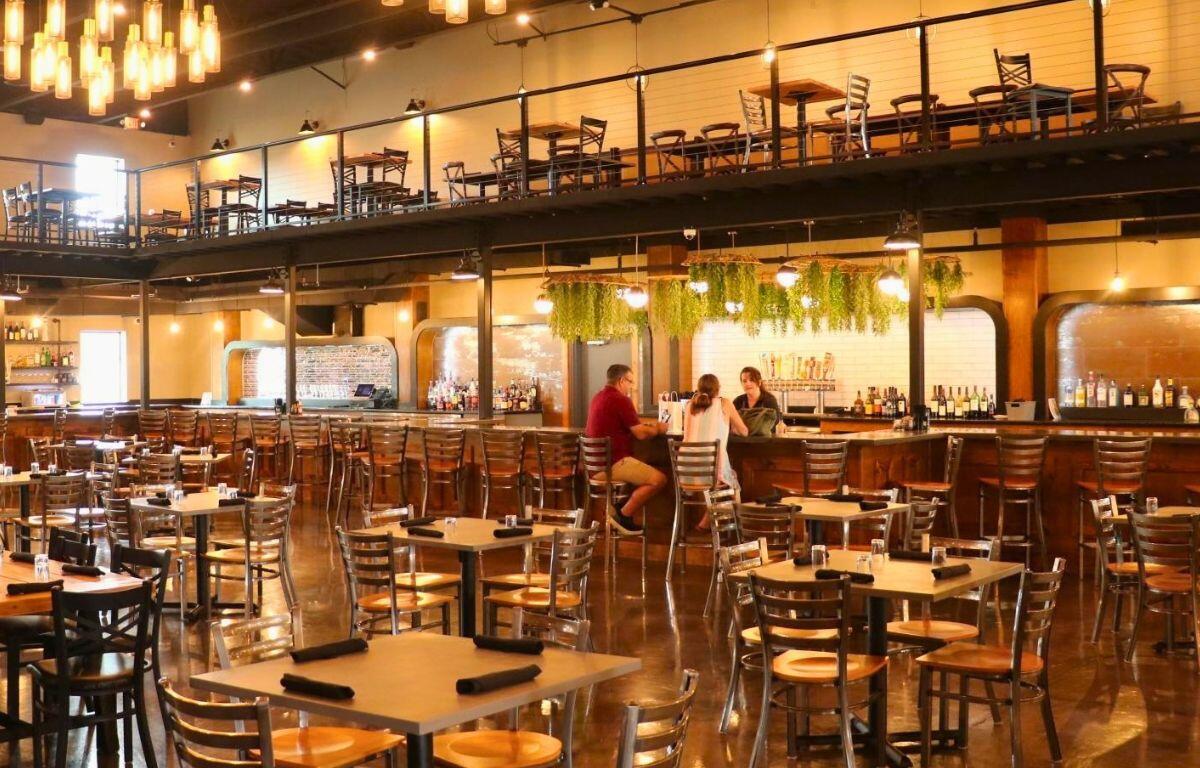 Large restaurant with tables on the ground floor and upper floor with a full bar lining the back wall.