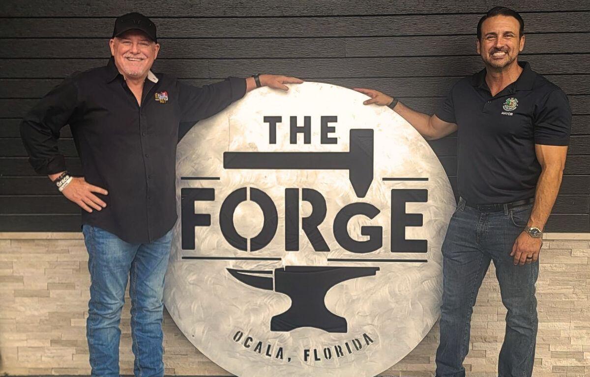 Two men next to a sign, "The Forge."