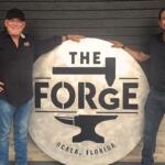 Two men next to a sign, "The Forge."