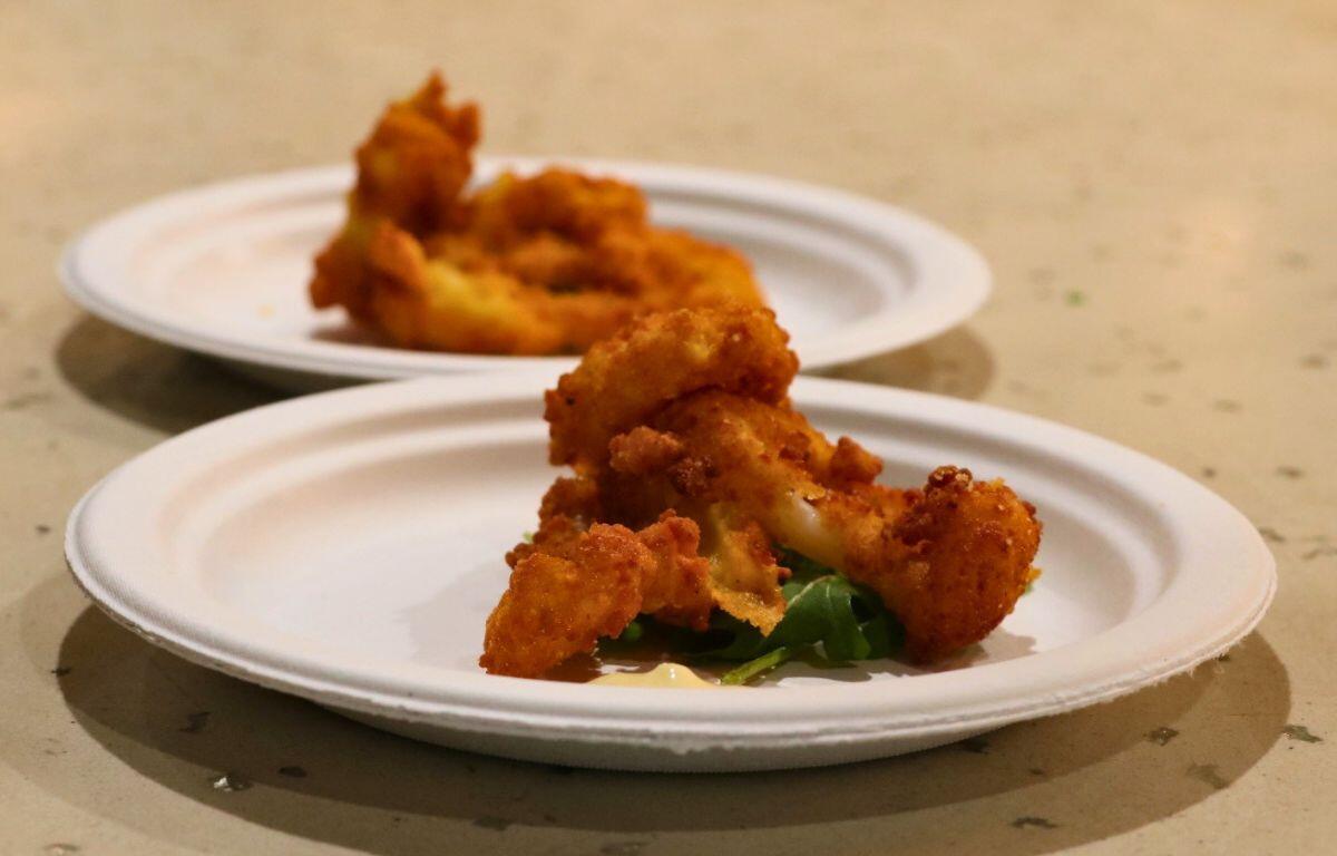 A paper plate with fried chicken and greens.