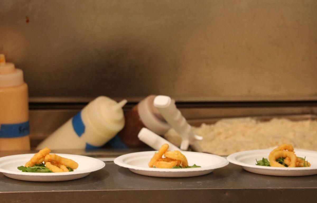 Samples of food sit on paper plates on kitchen counter.