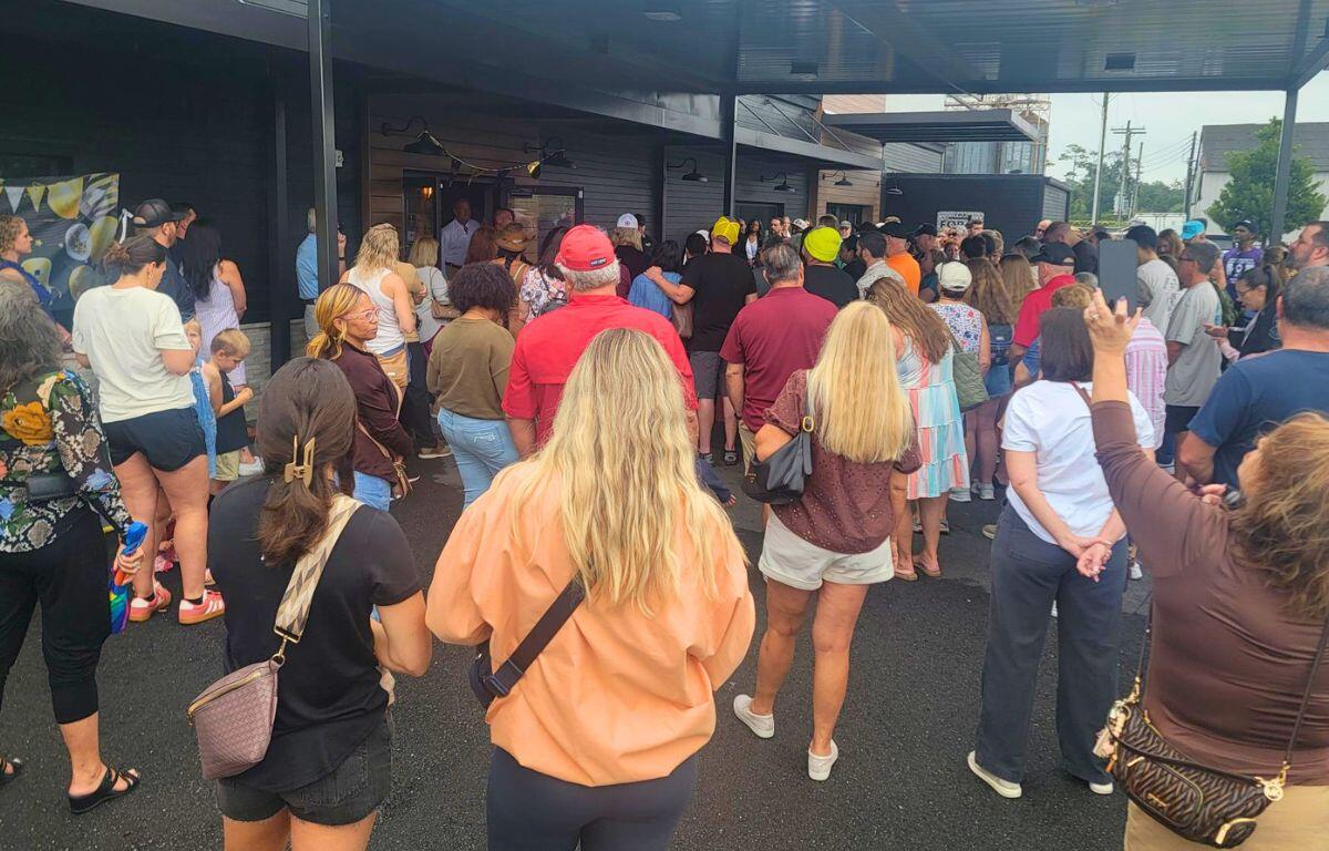 Crowd of people wait to enter building.