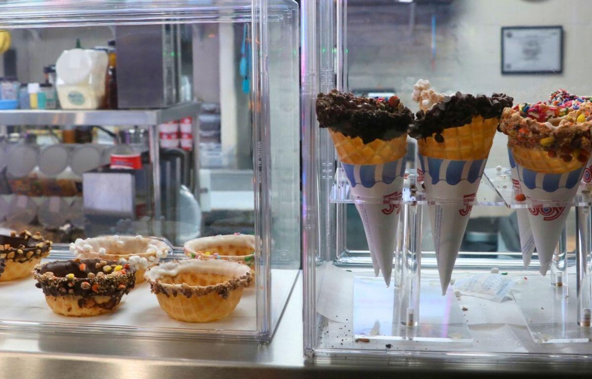 Ice cream cones and cone cups in display cases on counter.