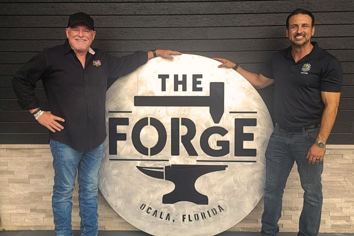 Two men next to a sign, "The Forge."